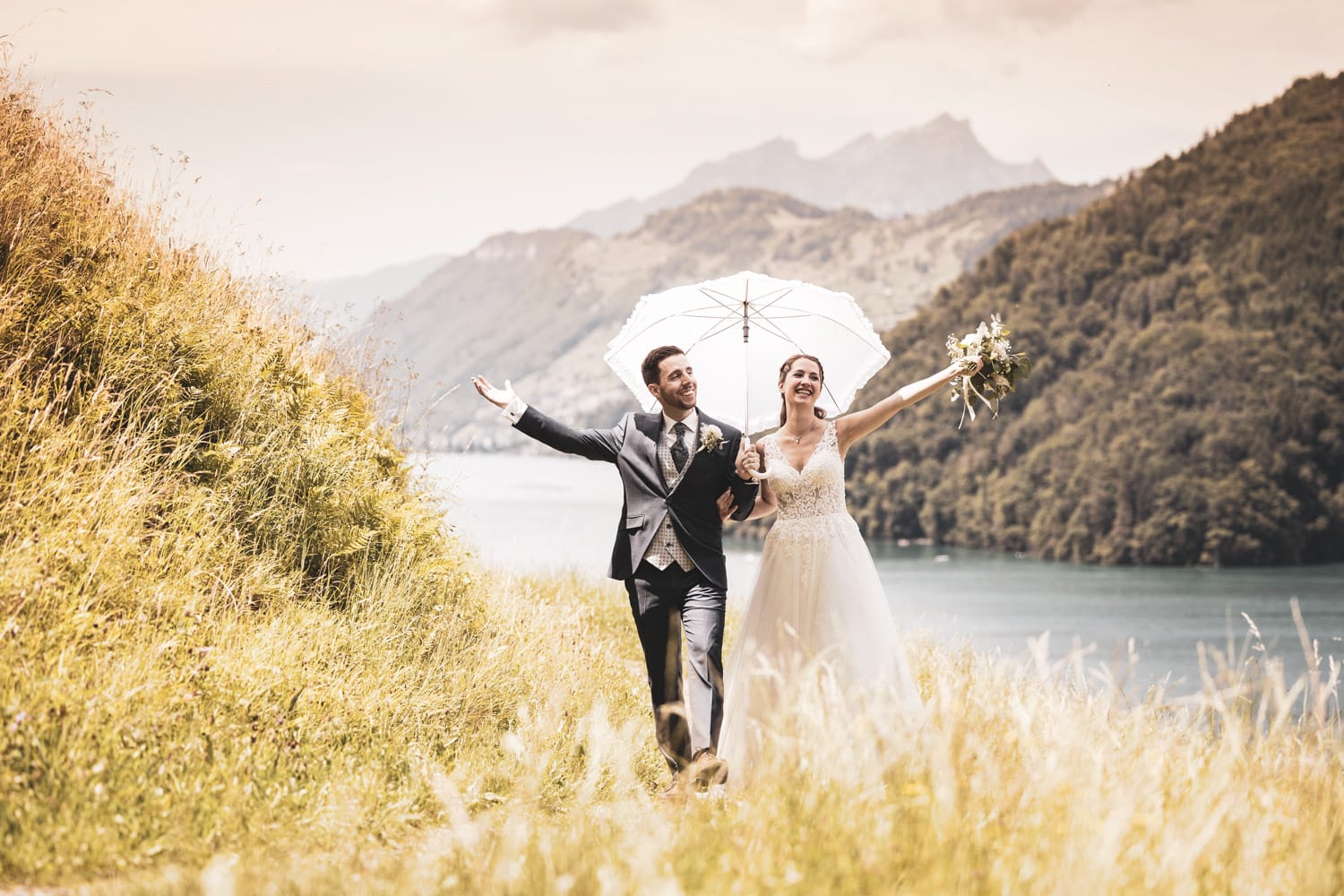 Brautpaar mit Sonnenschirm auf einem Wanderweg in Vitznau.