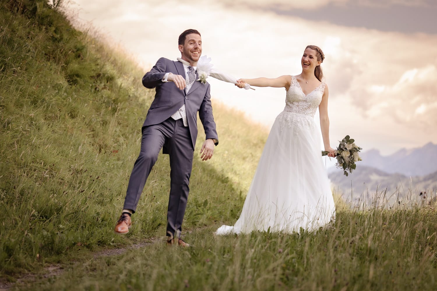 Lustiger Moment bei der Hochzeit – Braut zieht Bräutigam mit dem Sonnenschirm.